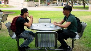 two students sitting at outside table on campus