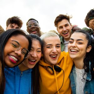 Group of multiracial teen college friends having fun outdoors. Happy people taking selfie. Gen z, friendship and technology concept.